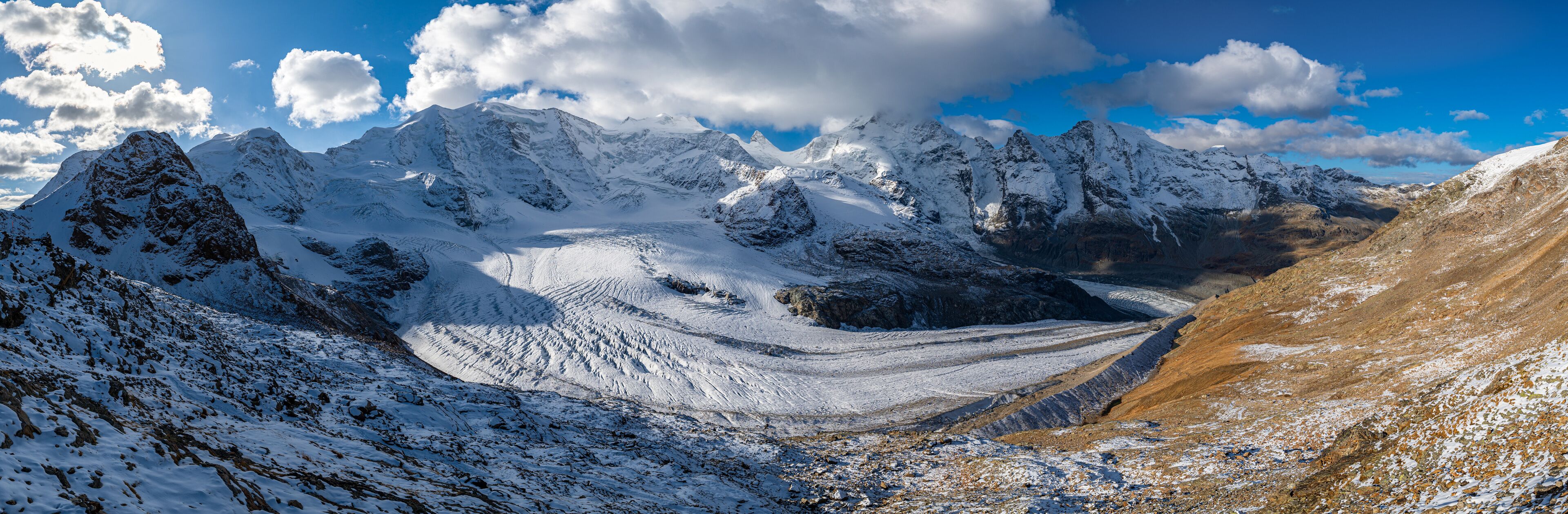 Cordillera nevada con un glaciar y terreno rocoso.