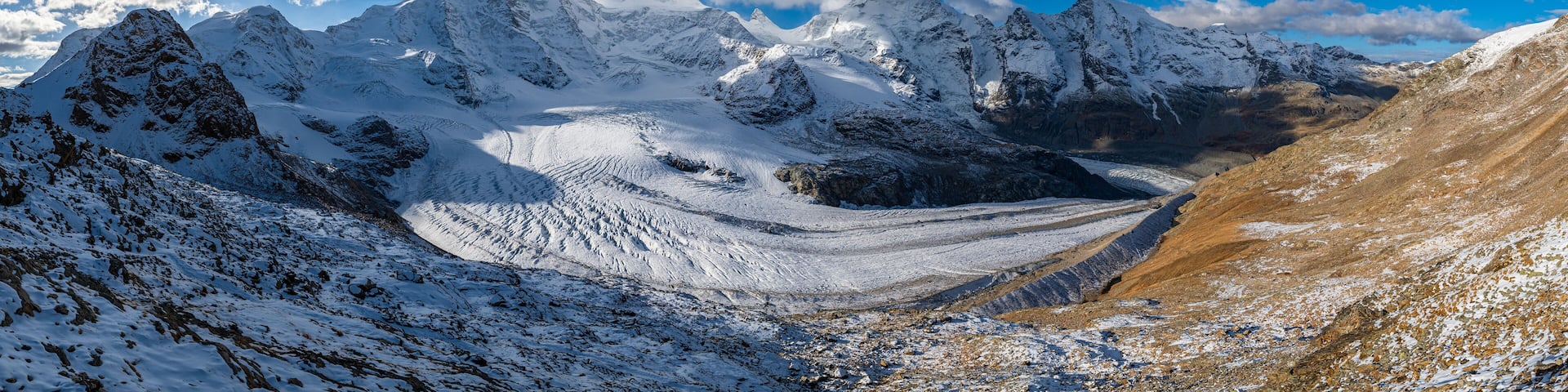 A snow-covered mountain range with a glacier and rocky terrain.