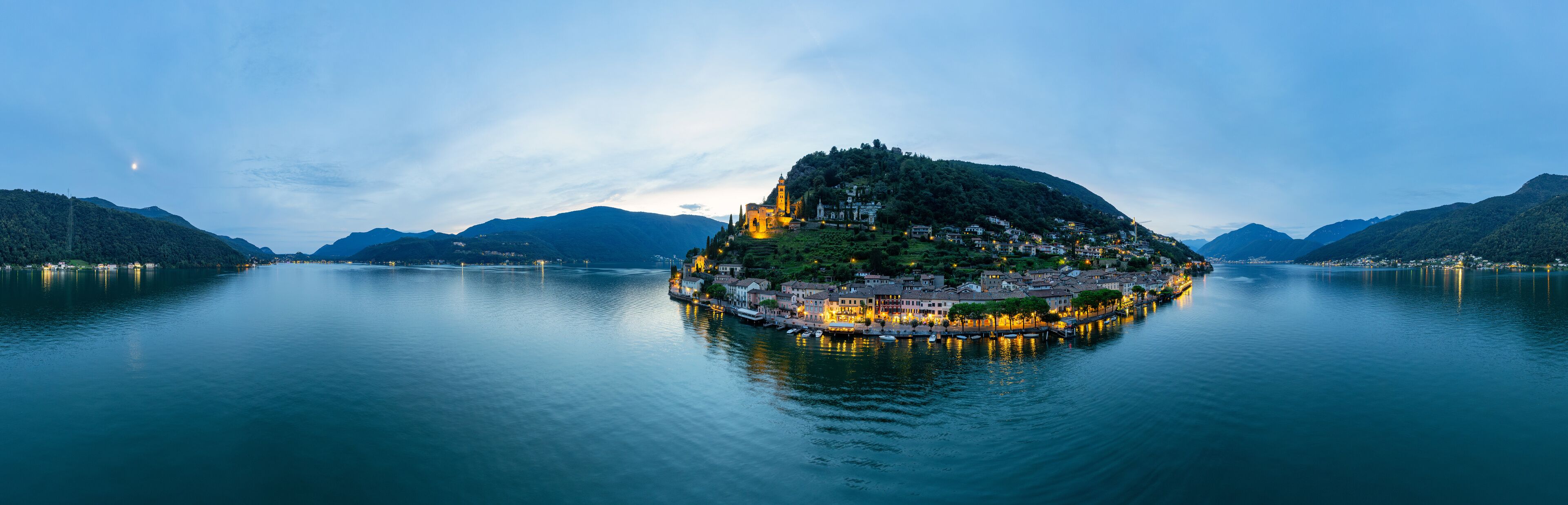 A serene lake with a small island featuring a church and residential buildings.