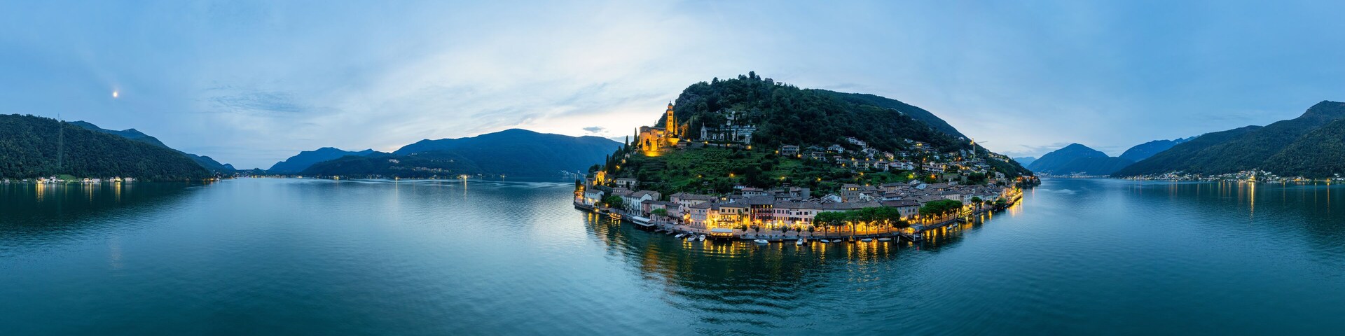 A serene lake with a small island featuring a church and residential buildings.