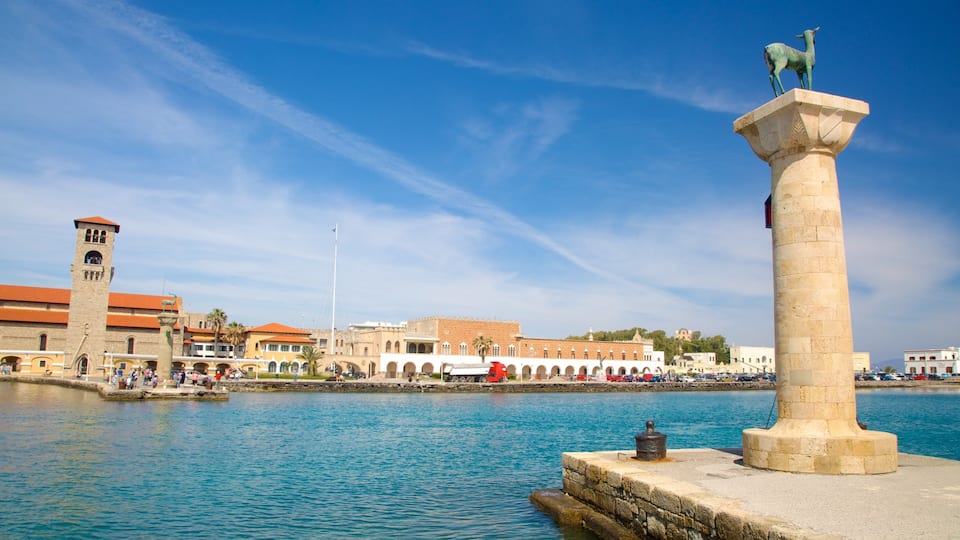 A coastal cityscape with a prominent tower, a large statue, and a historic building with a patterned facade.