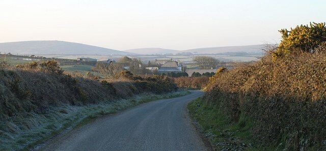 Lane to Treglasta The farm is visible above the banks of the lane. Beyond is a good view across the valley of the Inny towards Bodmin Moor.