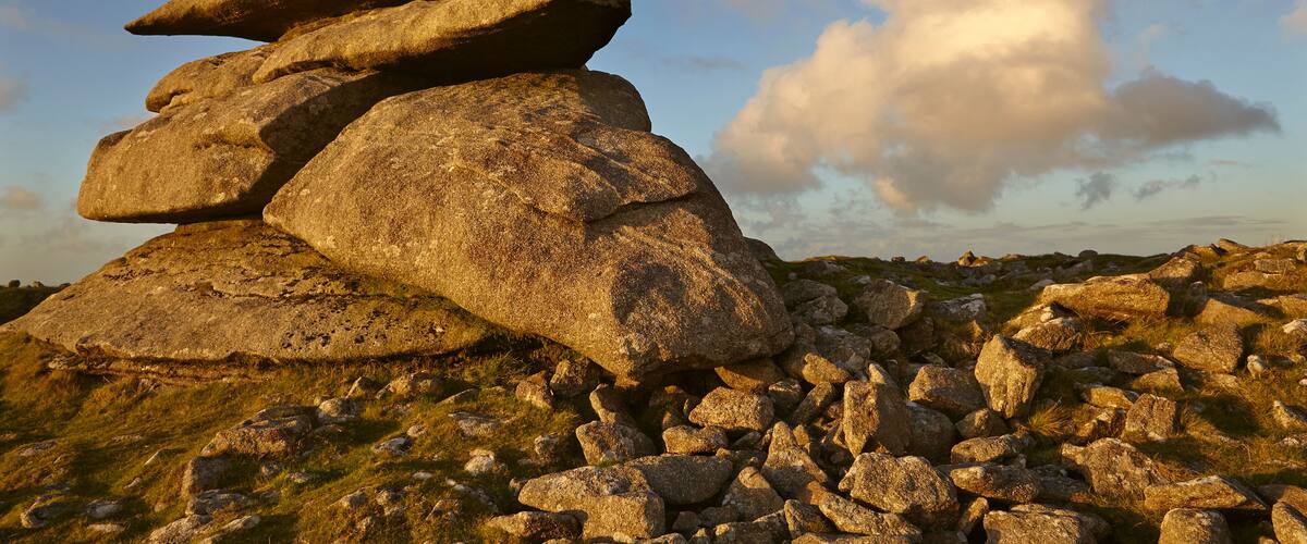 Un conjunto de grandes rocas sobre un campo cubierto de hierba, con cielo despejado.