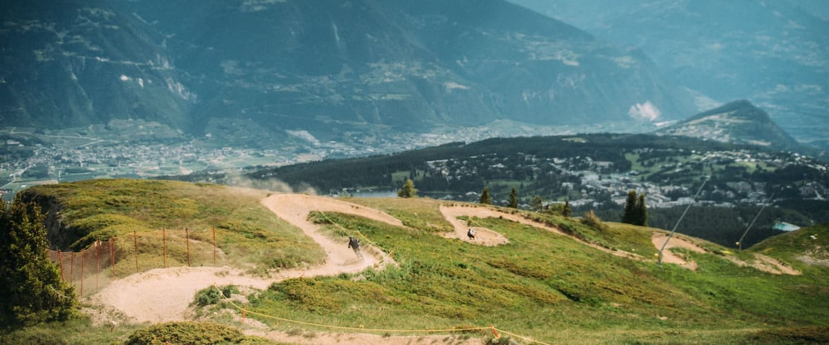 A mountainous landscape with a valley, a river, and a town in the distance.