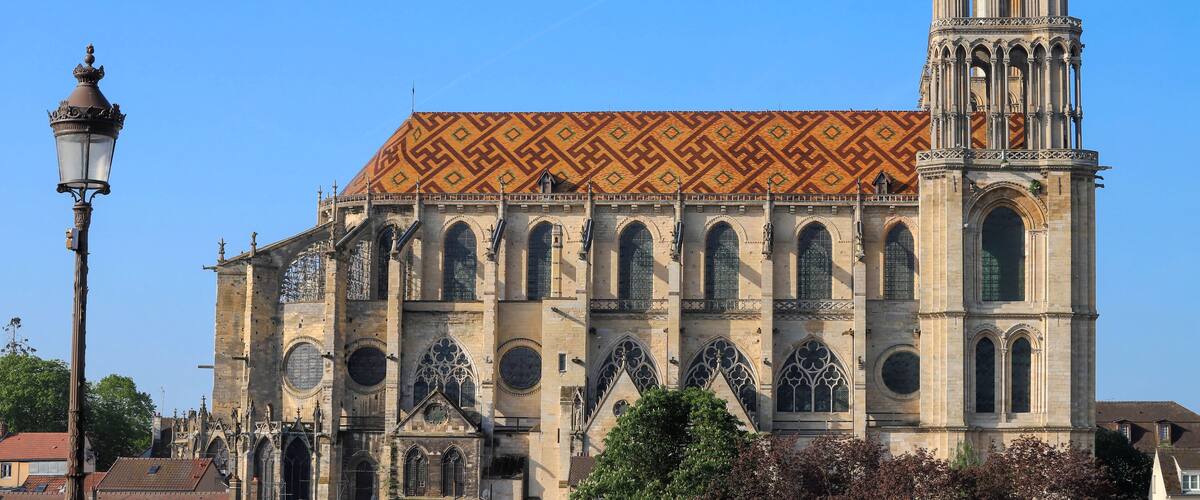 A historic cathedral with a patterned roof and a tall bell tower.