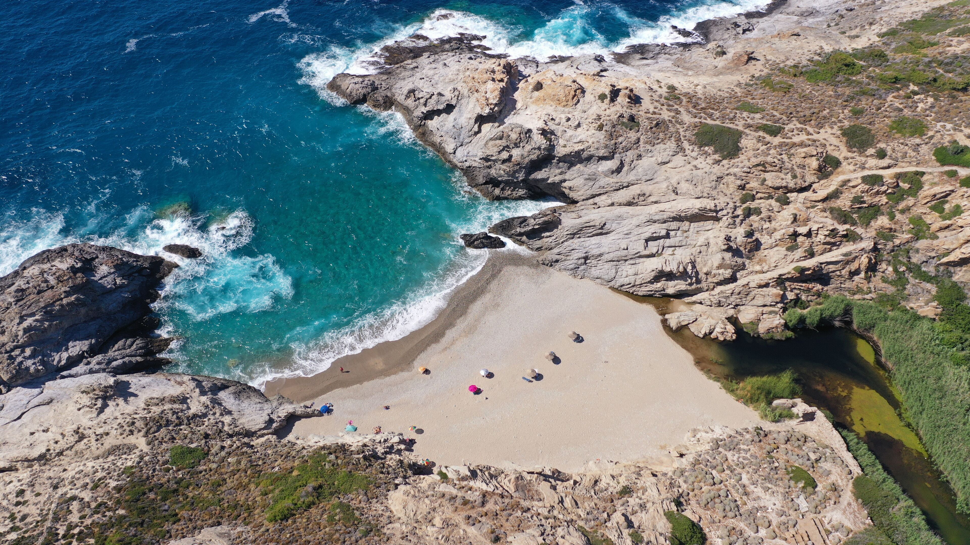 Una costa rocosa con una playa de arena y aguas azul turquesa.