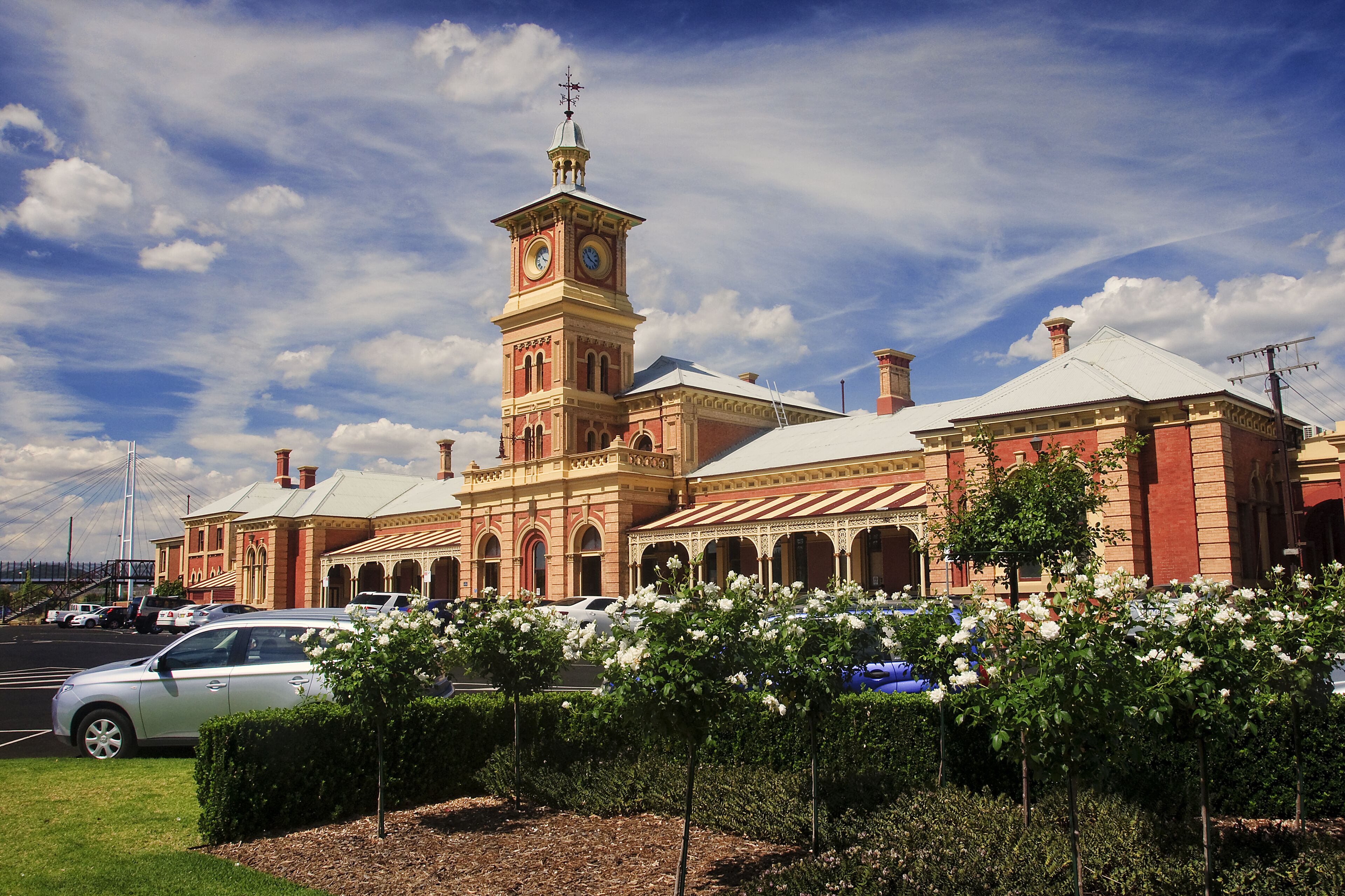 A historic building with a clock tower, arched windows, and a covered walkway.