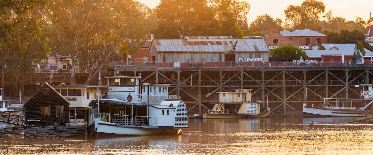 Panorma view of historic paddle steamers beside an old river port in golden evening light