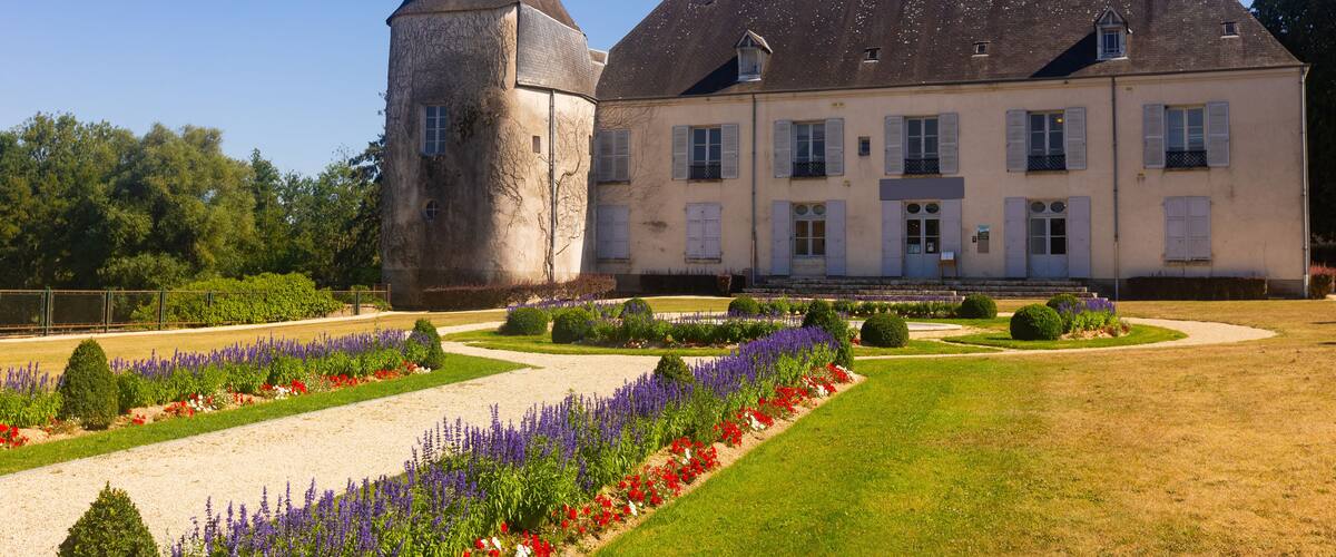 A large estate with a prominent tower, manicured gardens, and a well-maintained lawn.