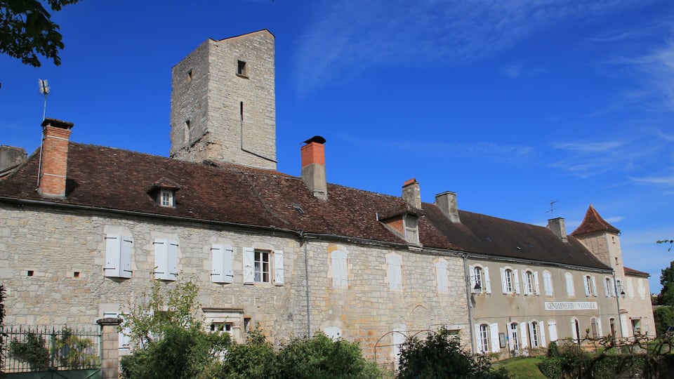 A historic stone building with a tower and multiple chimneys.