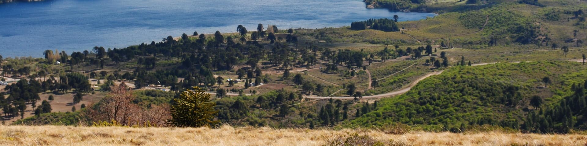 A mountainous landscape with a large lake surrounded by hills and a small village.