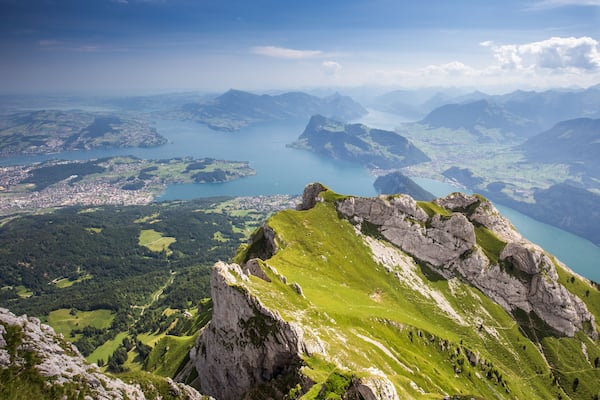 Un paysage montagneux avec un lac, des vallées verdoyantes et des pics rocheux.