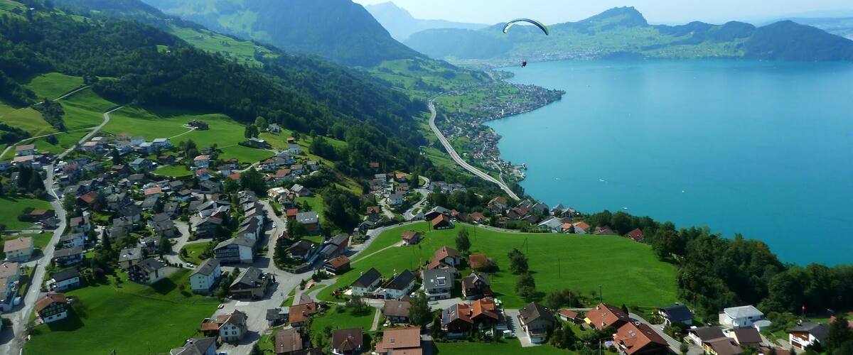 A coastal town with a lake, surrounded by green hills and mountains.