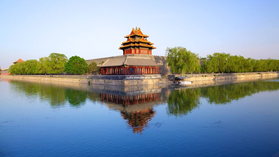A traditional Chinese building with a multi-tiered roof, reflecting in calm water.