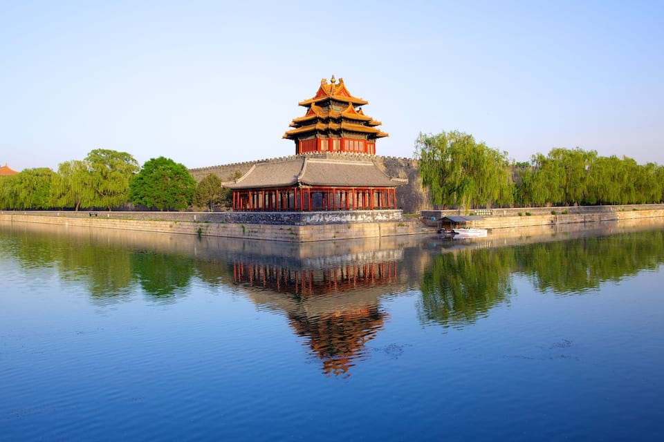 Un bâtiment traditionnel chinois, doté d’un toit à plusieurs niveaux, qui se reflète dans l’eau calme.