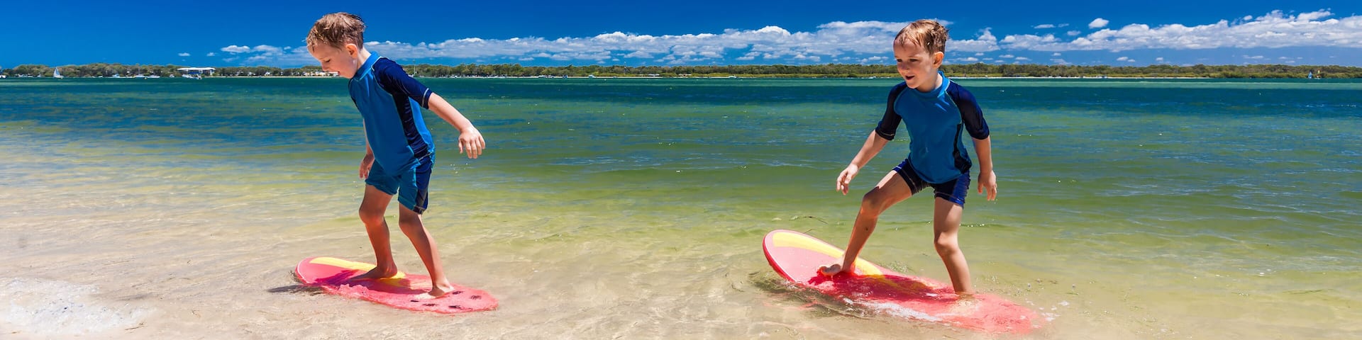 Surfer twin brothers have fun on beach learning to surf