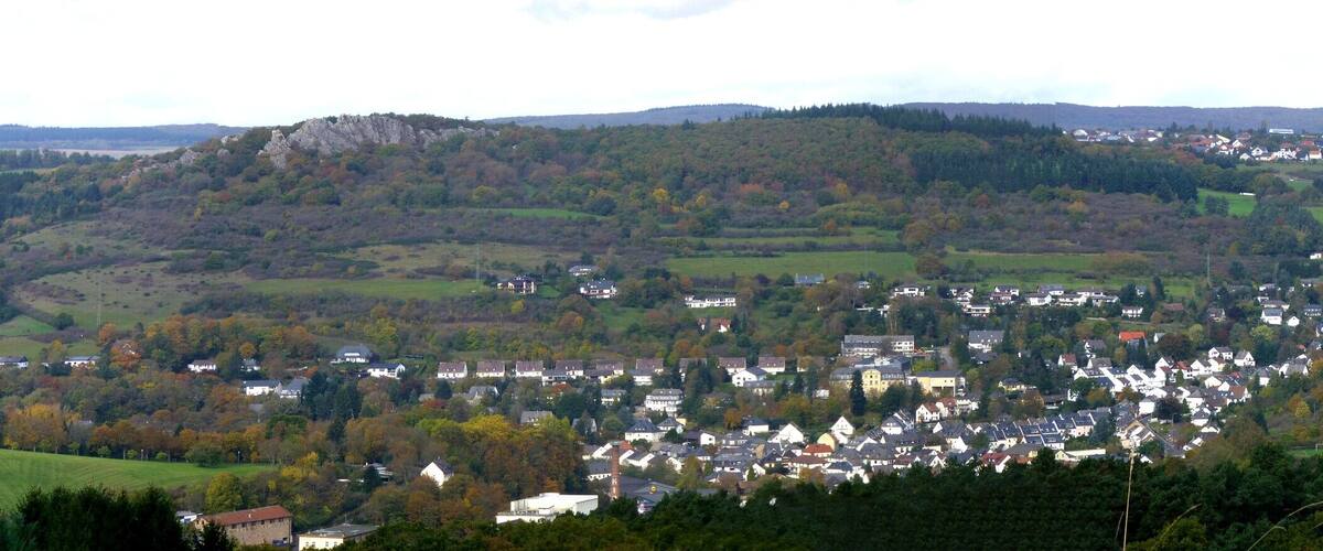 A town nestled in a valley with rolling hills and scattered houses.