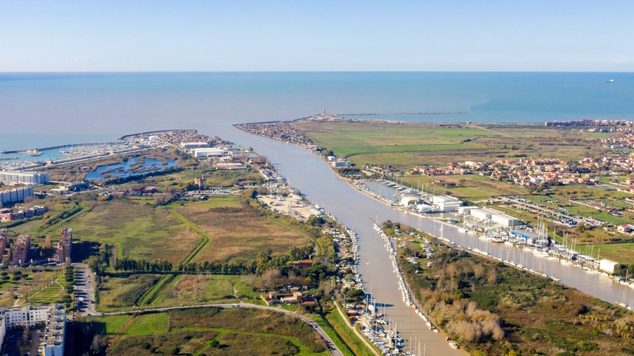 Una ciudad costera con río, puerto deportivo y edificios industriales.
