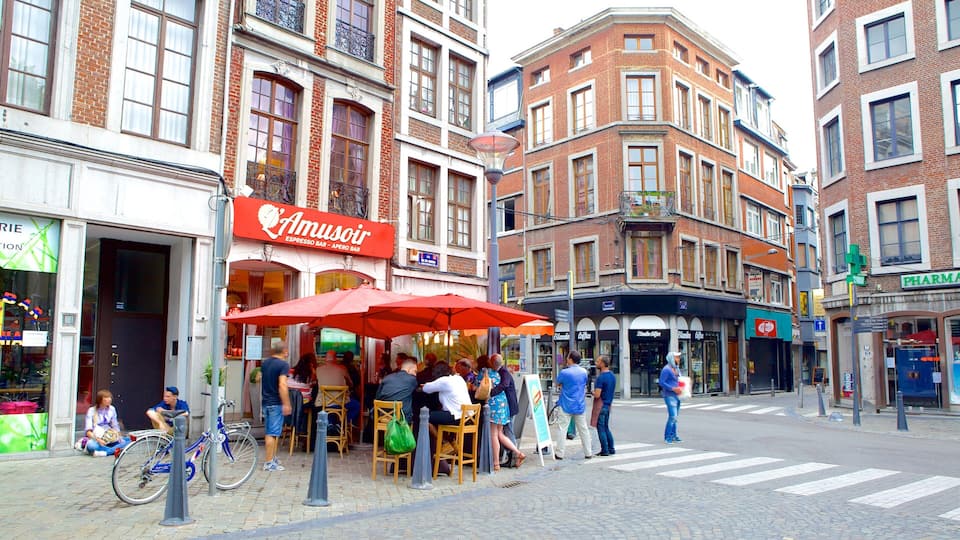 A street with a red umbrella café, a pharmacy, and a pharmacy sign.