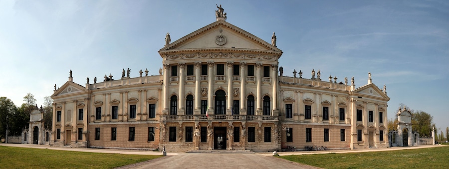 Un imposant bâtiment de style néoclassique, doté d’une façade symétrique, de grandes colonnes et de statues.