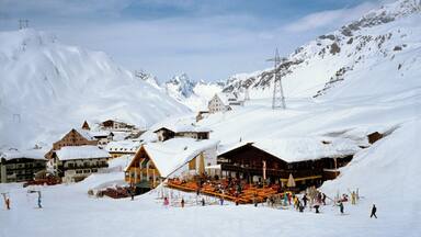 A snow-covered ski resort with buildings, a ski lift, and a mountainous backdrop.