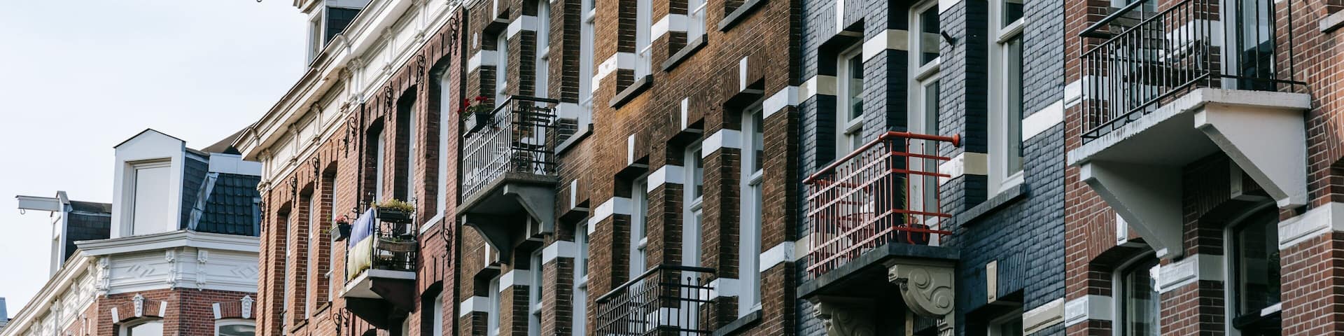 A row of red brick buildings with white trim and black railings on the balconies.