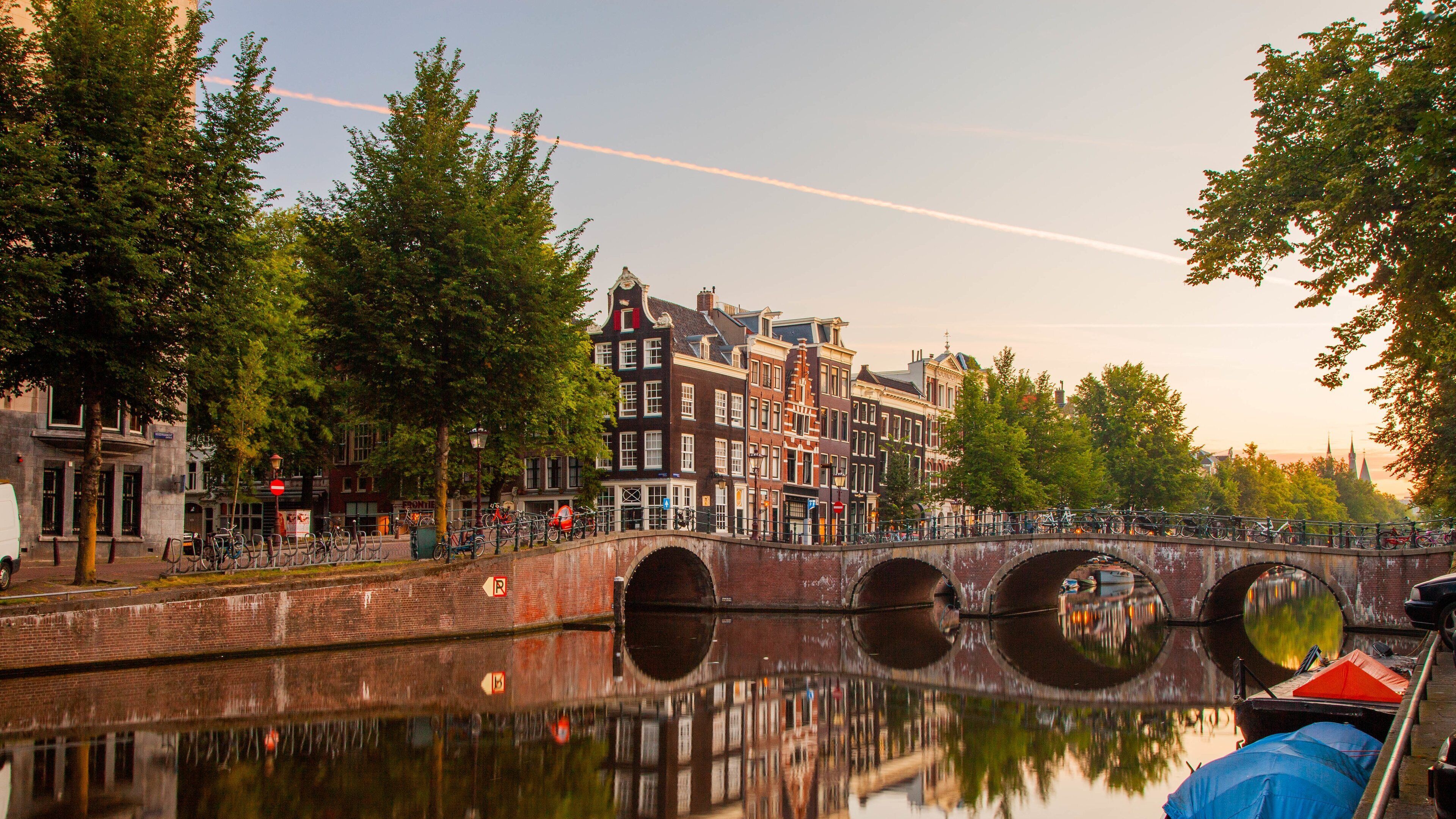A canal with a bridge, historic buildings, and trees reflecting in the water.