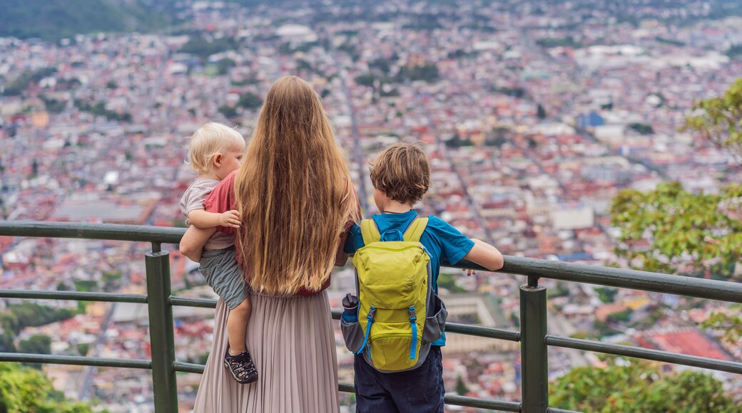 Mom and her two sons, a baby and a teenager tourists in front of the panoramic view of Orizaba from Cerro del Borrego, Mexico. Travel, scenic landscape, and adventure concept