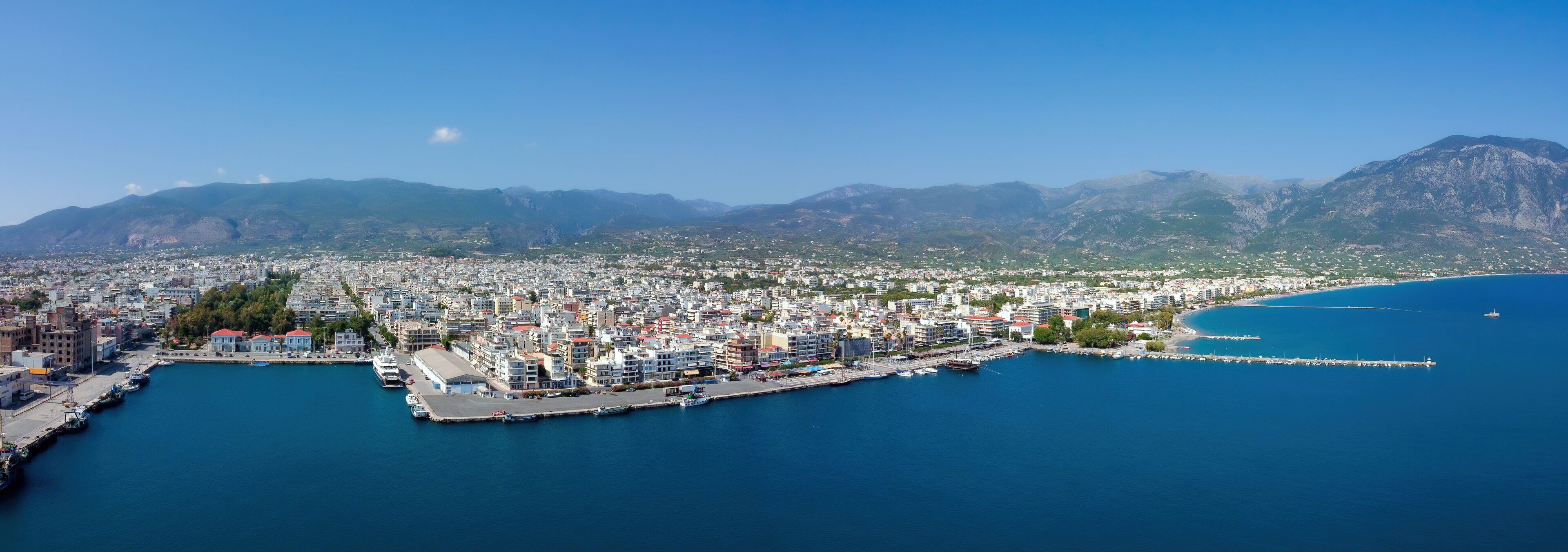 A coastal city with a marina, dense urban area, and mountainous backdrop.