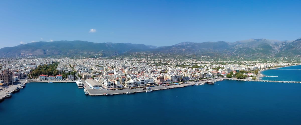 A coastal city with a marina, dense urban area, and mountainous backdrop.