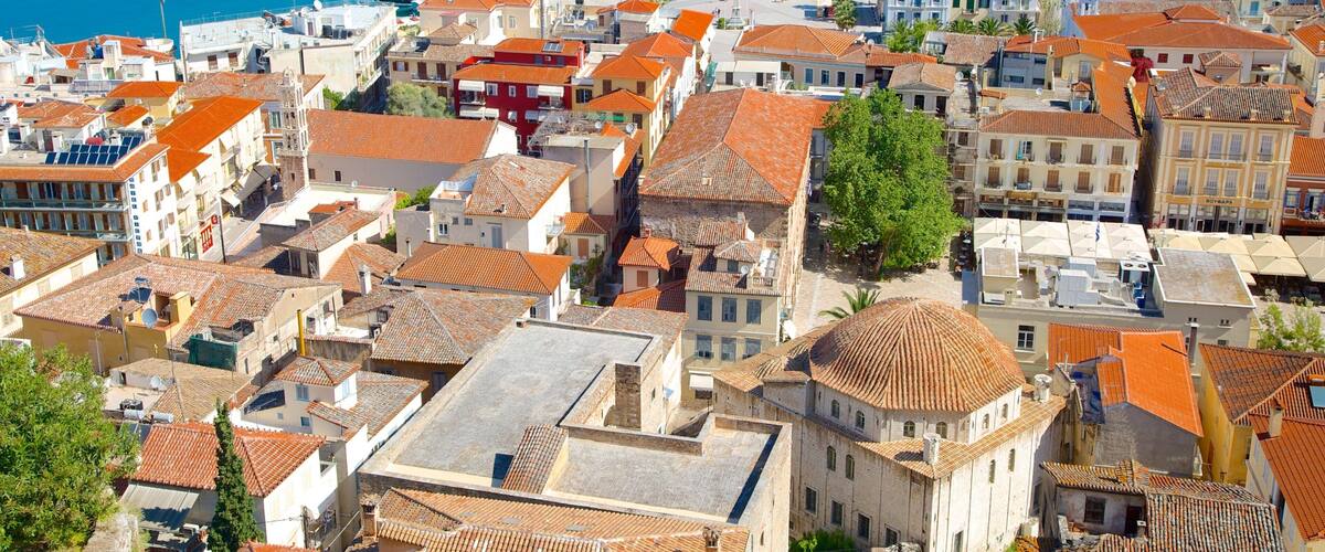 A coastal town with red-tiled rooftops, a marina with sailboats, and a clear blue sea.