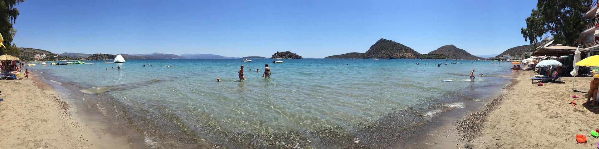 Uma praia com águas cristalinas, pessoas nadando e barcos.