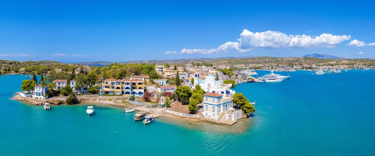 A coastal town with buildings surrounded by turquoise waters and boats.
