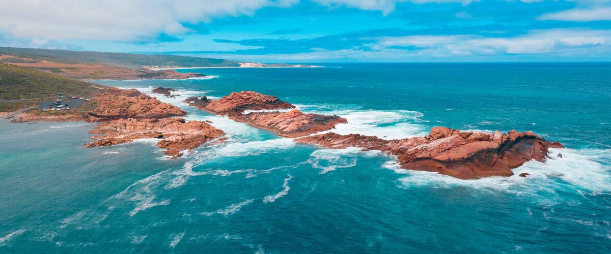 A coastal landscape with rocky formations and a clear blue sea.