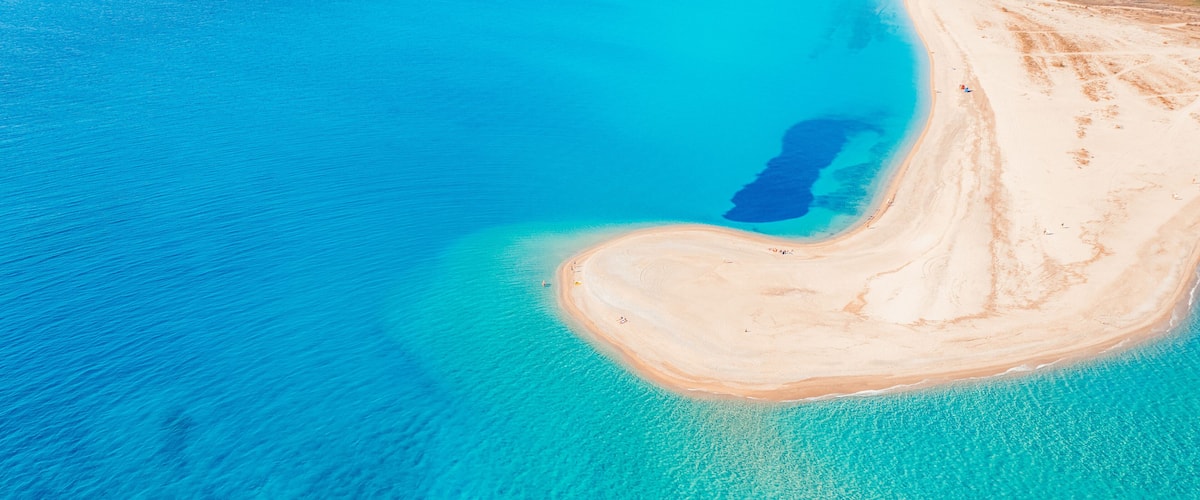 An aerial view of a turquoise lagoon with a sandy beach and a small island.