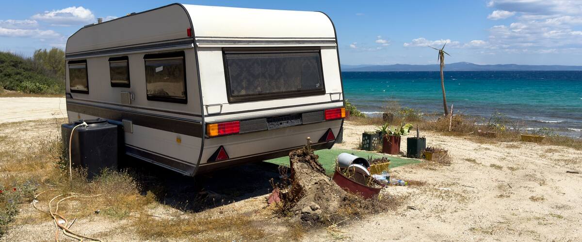 A white RV parked on a sandy beach with the ocean in the background.