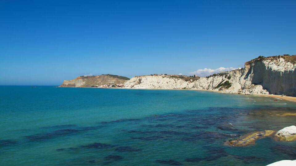 A coastal landscape with clear blue waters, sandy beaches, and white cliffs.