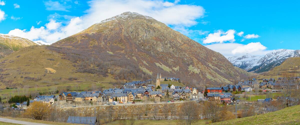 A mountain town with buildings nestled in a valley, surrounded by snow-capped mountains.