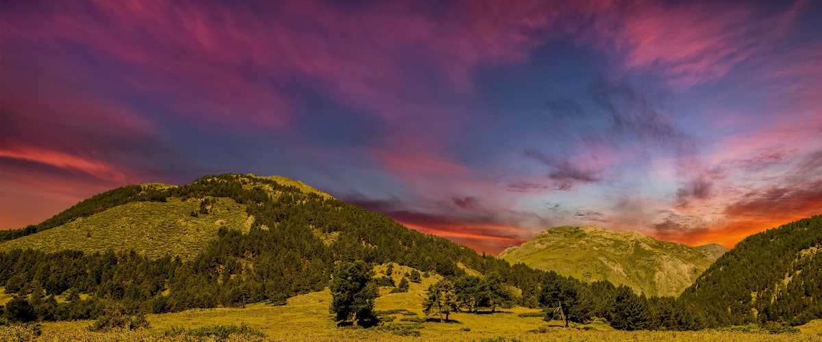 A mountainous landscape with a vibrant sky at sunset.