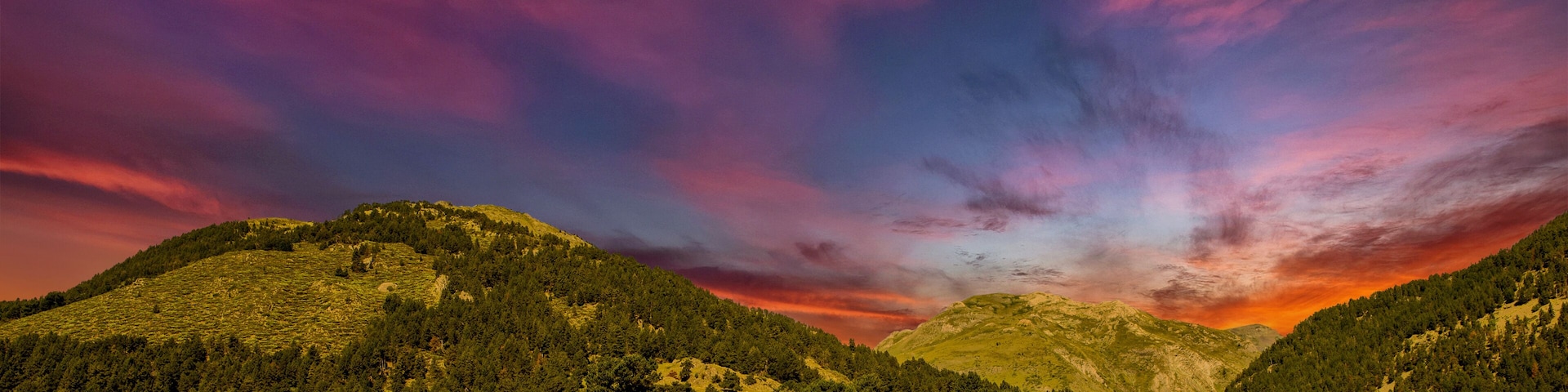 A mountainous landscape with a vibrant sky at sunset.