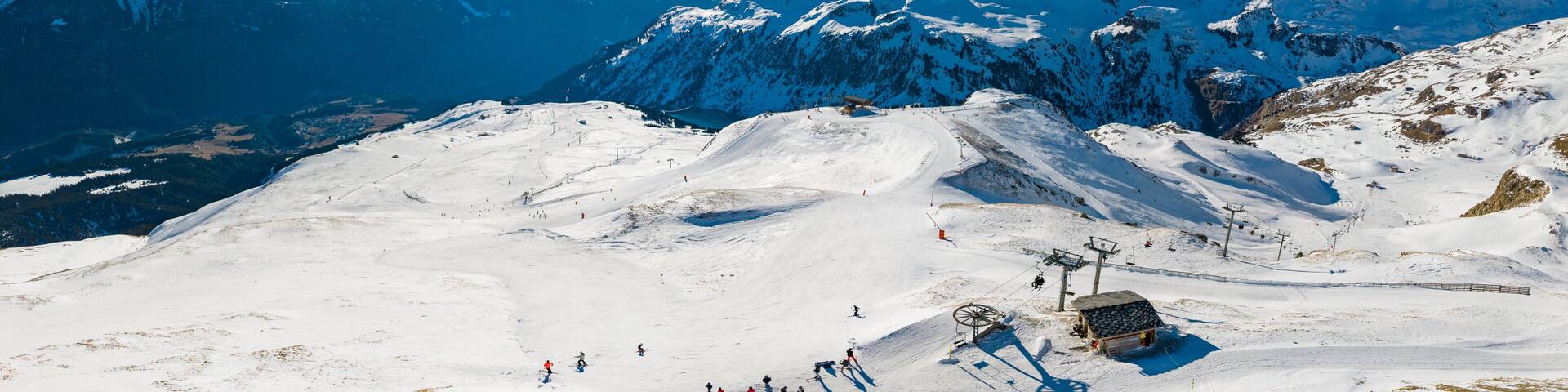A snow-covered mountain range with a ski lift and a clear blue sky.