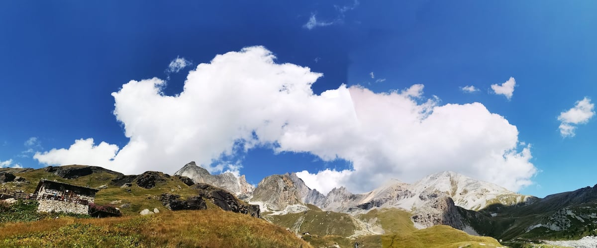 A mountainous landscape with a clear blue sky and a small stone building in the foreground.