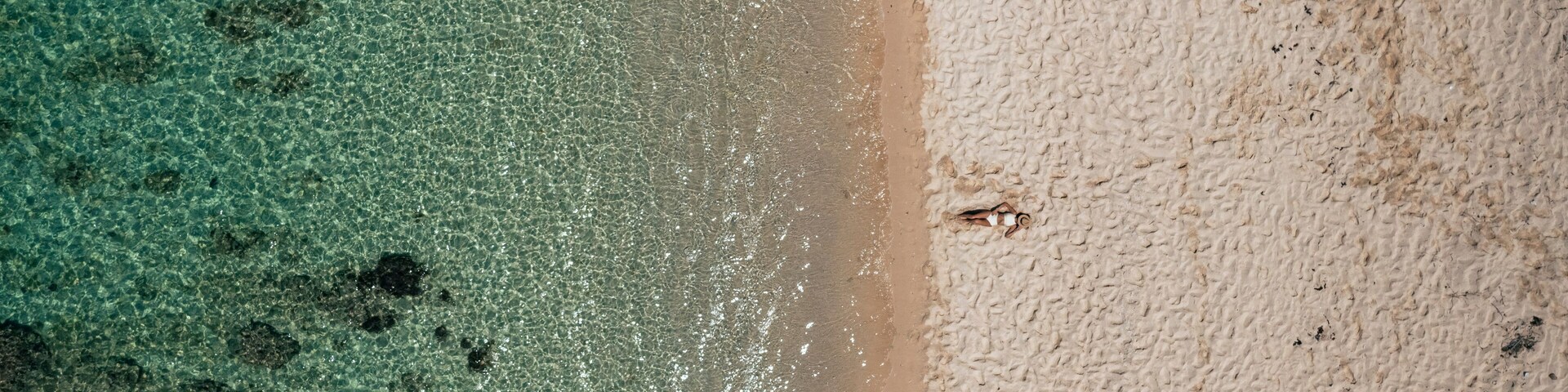 Aerial view of a woman relaxing on Pomponette Public beach along the shoreline, Chemin Grenier, Savanne District, Mauritius.