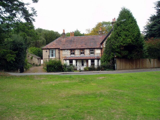 A traditional stone house with a tiled roof, surrounded by a grassy yard and a wooden fence.