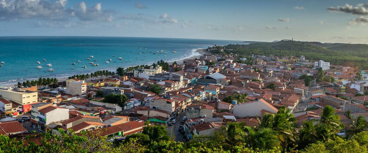 A coastal town with a beach, boats, and a hilly landscape.