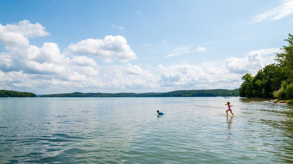 A calm lake with a person in blue and a child in pink.