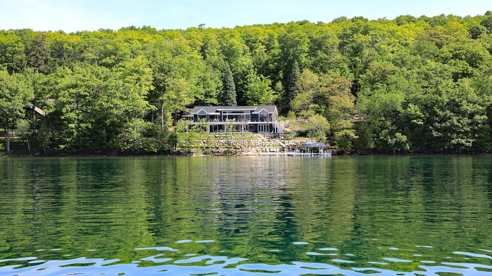 A lakeside house surrounded by dense forest.