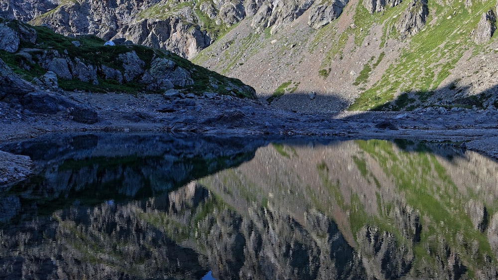 Un paysage de montagne se reflétant clairement dans un plan d’eau calme.