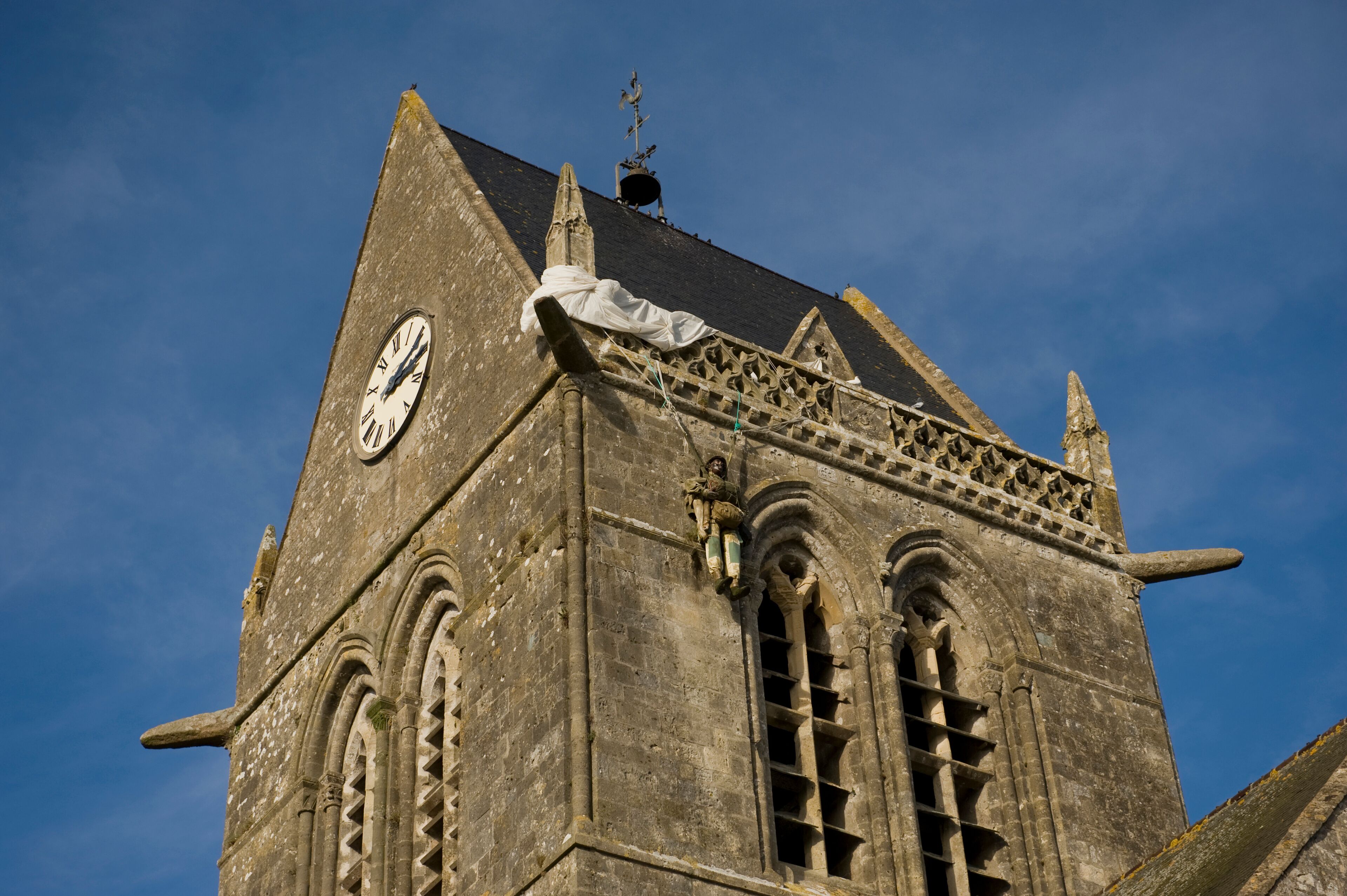 A historic building with a clock, pointed roof, and intricate stonework.