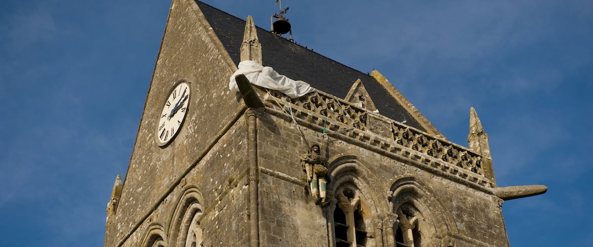 A historic building with a clock, pointed roof, and intricate stonework.